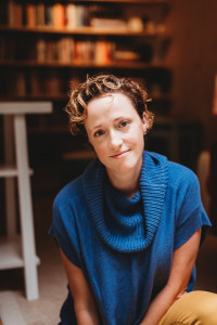 Photo of a woman with short, curly hair wearing a blue sweater