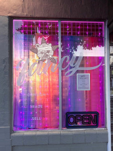A storefront that sells fancy clothes with the Self Help Radio logo superimposed on it.